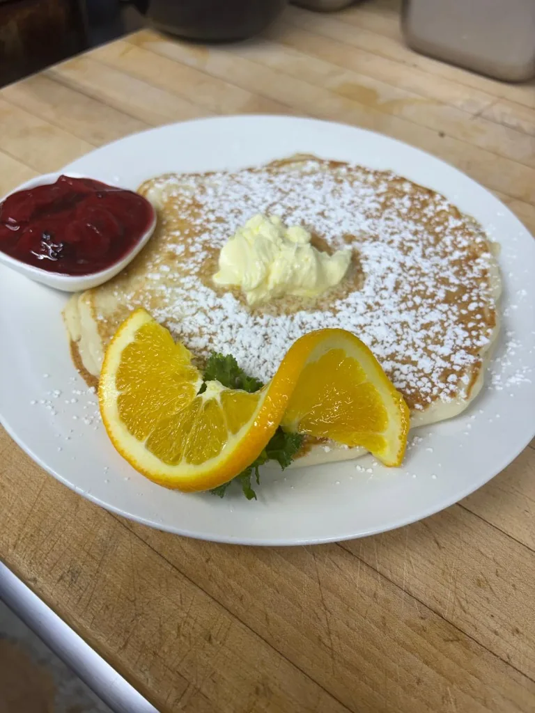 Chef Duke's signature Lemon Ricotta Pancakes topped with whipped lemon butter, powdered sugar, and strawberry compote at Estime's Cafe Colonia NJ